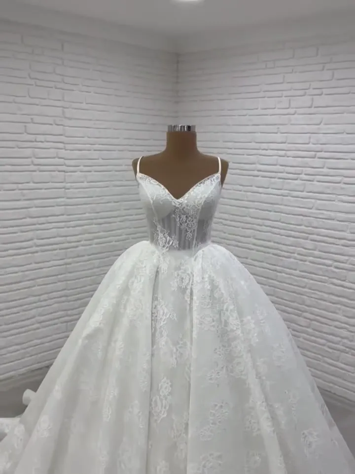 İnce askılı dantel prenses gelinlik, beyaz tuğla duvar önünde manken üzerinde önden.