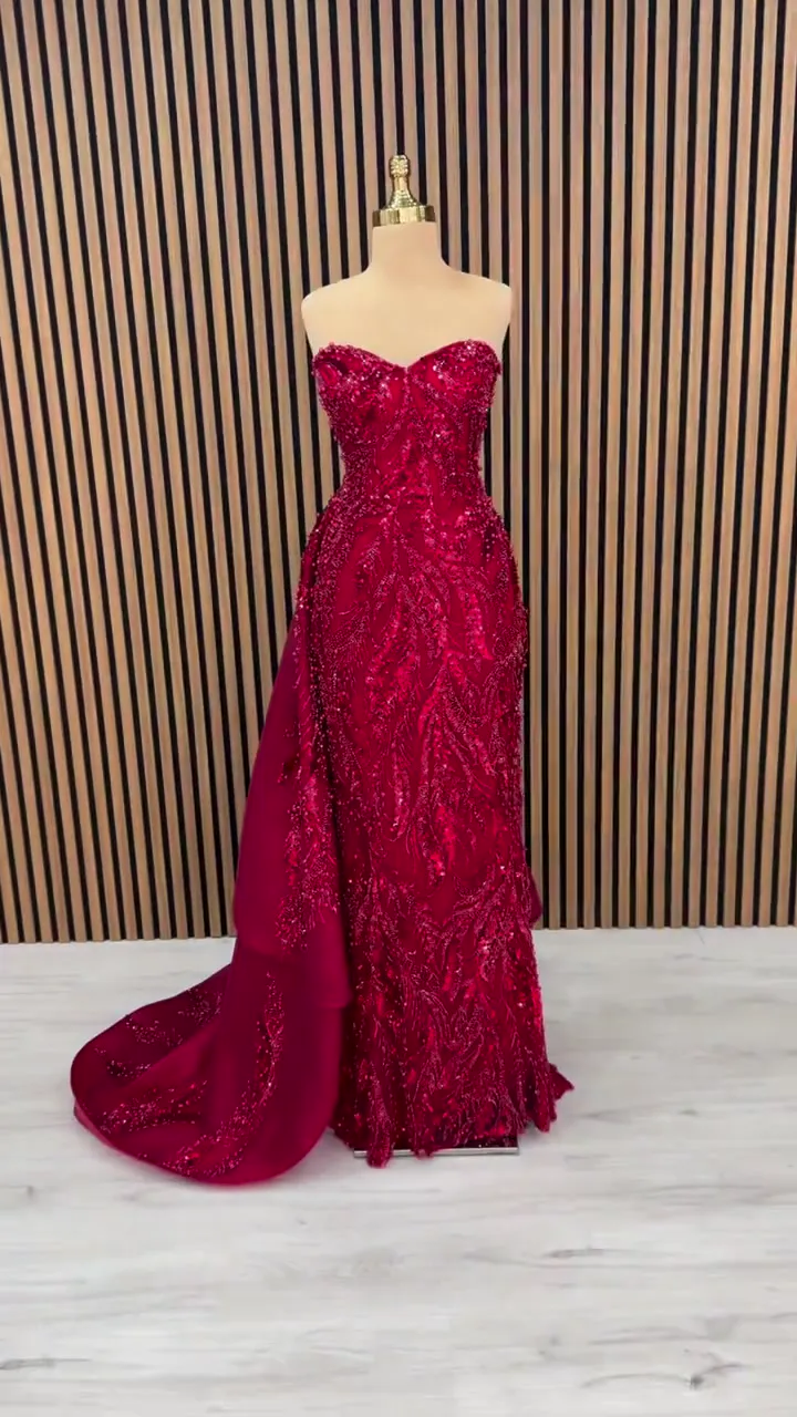 Kalp yaka yaprak taşlı dar kınalık, ahşap çıta önünde önden; kırmızı işlemeli dar gövde ve yanda açılan üst etek.
