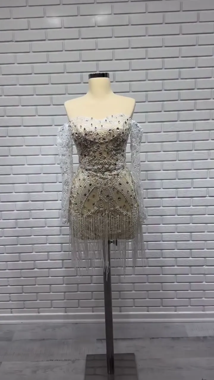 Kalp yaka bitkisel işlemeli püsküllü mini after party elbisesi, şampanya ve gümüş tonlarında duvar önünde önden.