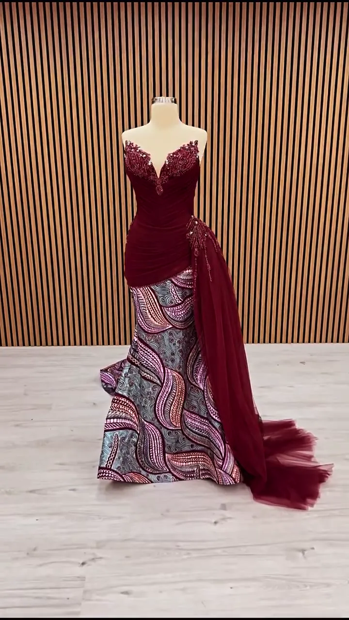 Drapeli V gövde desenli balık abiye önden; ahşap çıtalı duvar önünde bordo üst ve pembe gri mavi etek.