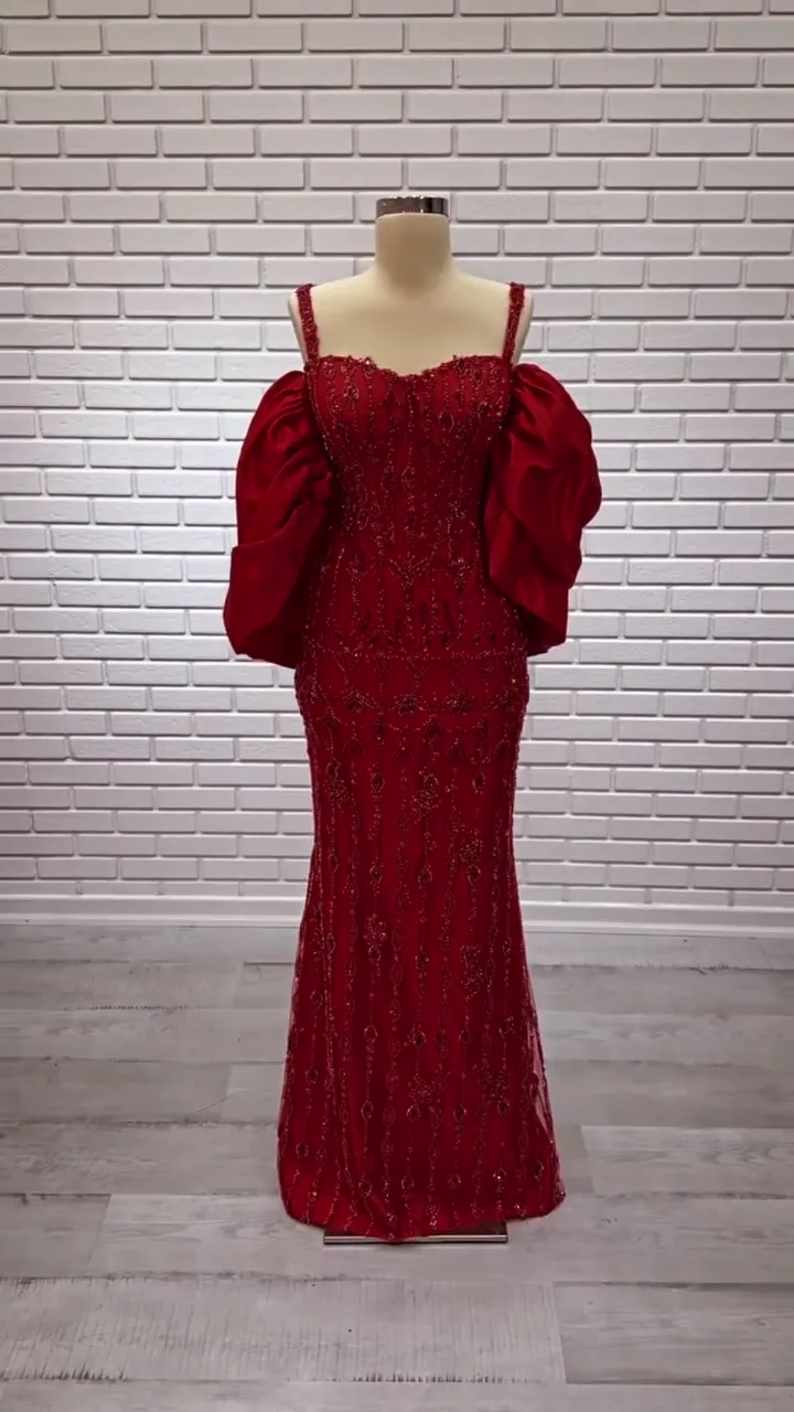 İnce askılı saten balon kollu dar kınalık önden; kırmızı taş dizileri ve hacimli kollar beyaz tuğla duvar önünde.